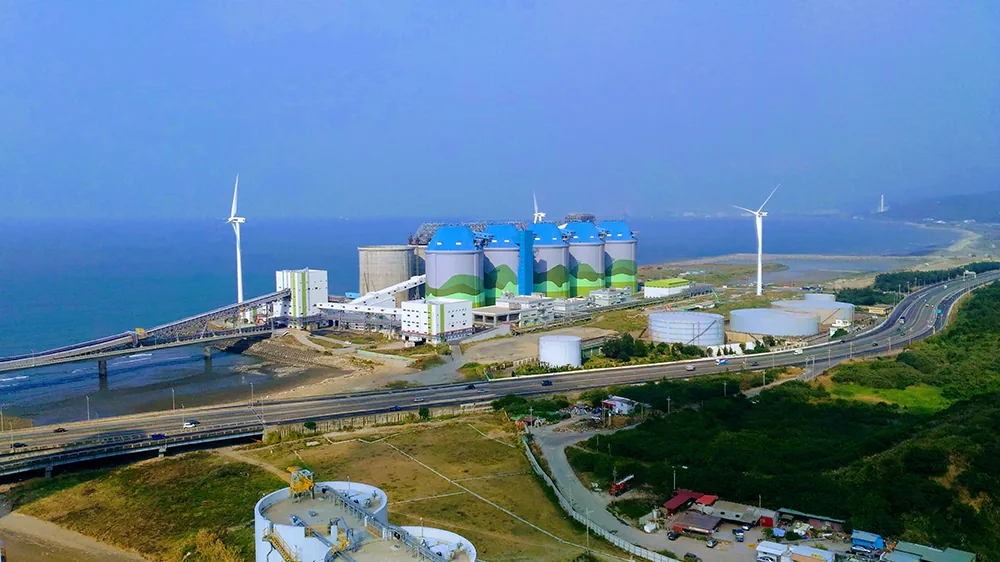 Wind turbines and storage tanks beside a coastal power plant