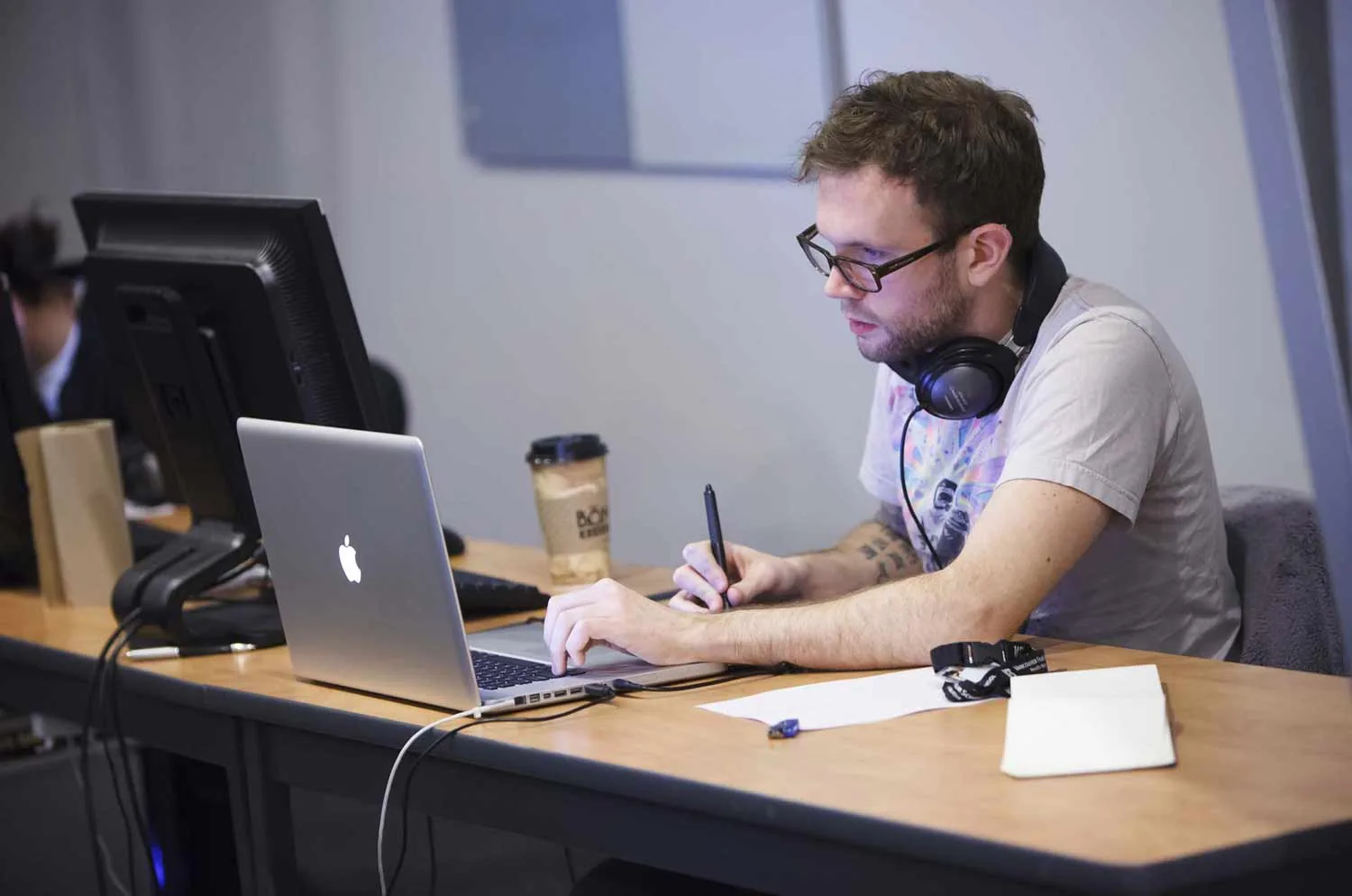 An engineer working at a laptop with headphones on